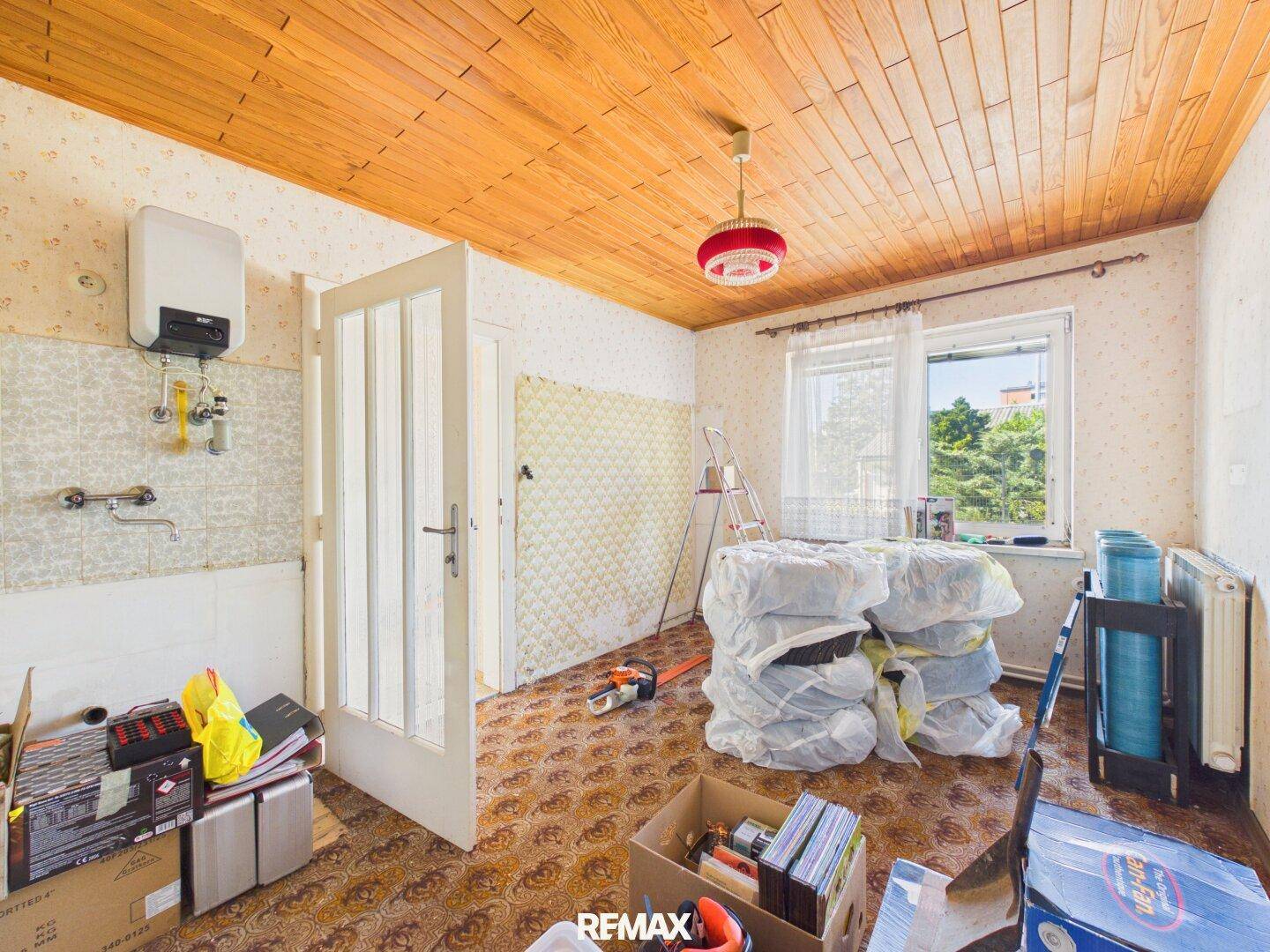 Raum mit Spüle, Warmwasserbereiter und Fenster, bereit für Kücheneinbau oder Nutzung als Hauswirtschaftsraum.