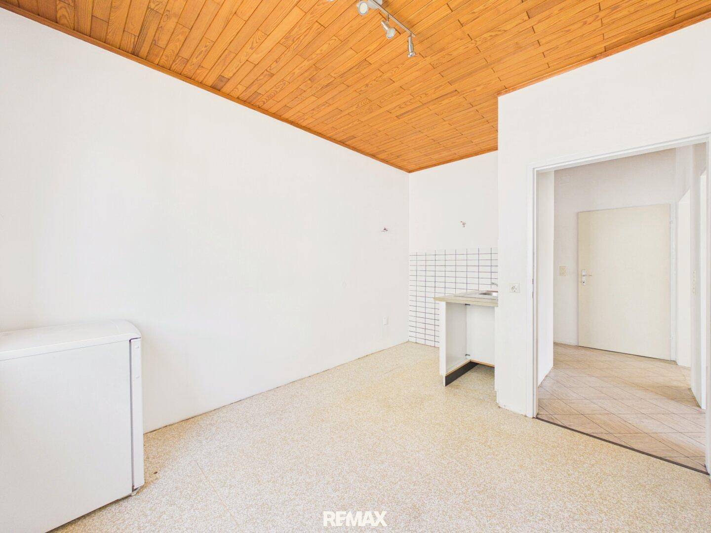 Einfache Küche mit Holzpaneeldecke und Terrazzoboden, bereit für Modernisierung.