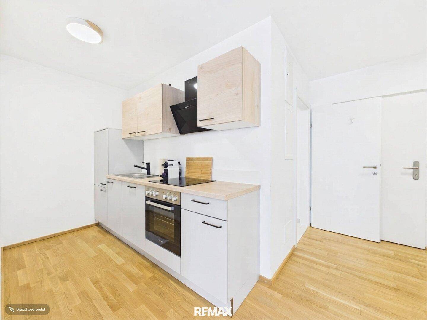 Moderne Einbauküche mit hellen Holzschränken, Kochfeld, Backofen und Dunstabzugshaube.