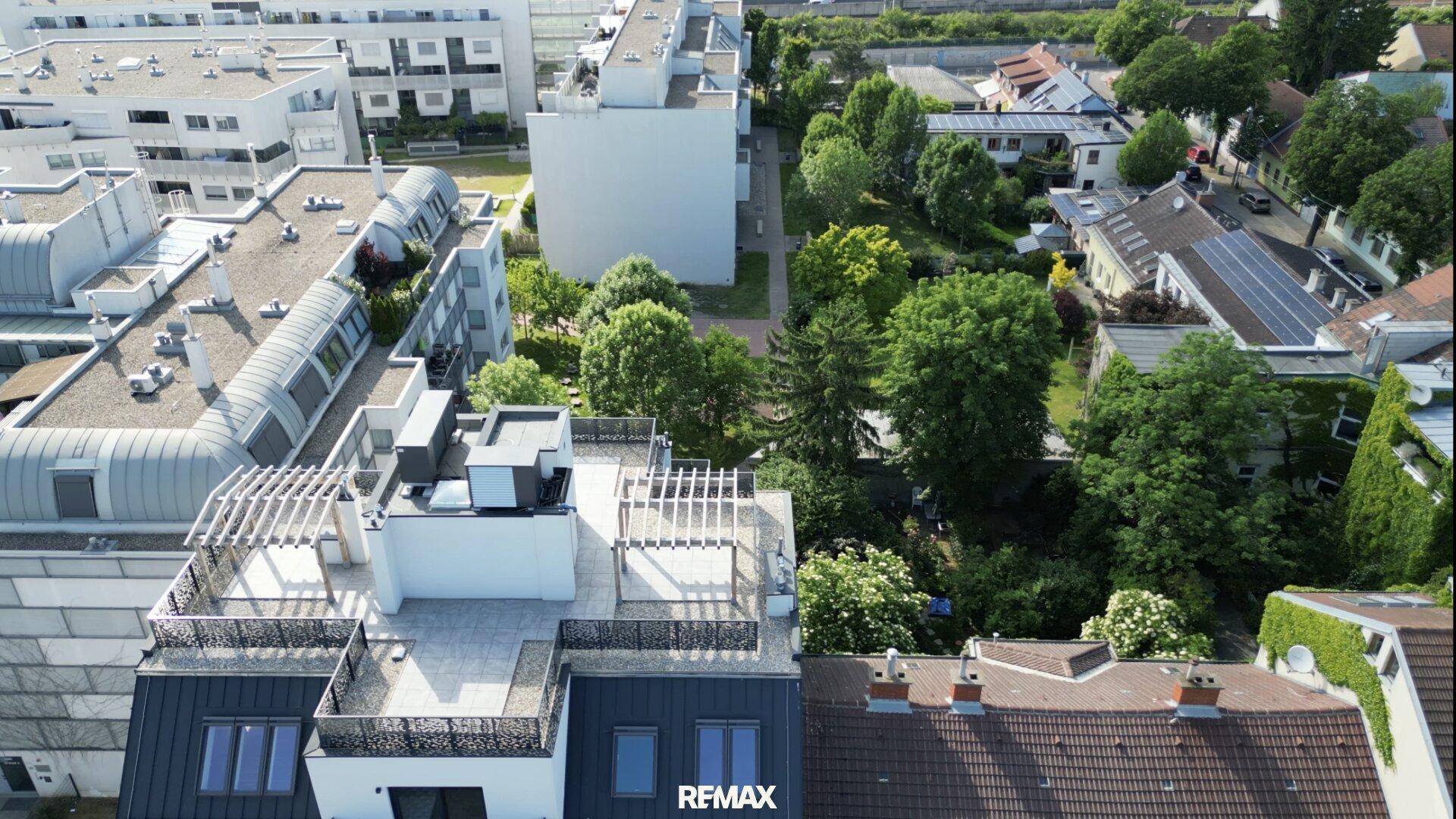 Luftaufnahme des modernen Wohngebäudes mit Dachterrassen und der umliegenden grünen Umgebung.