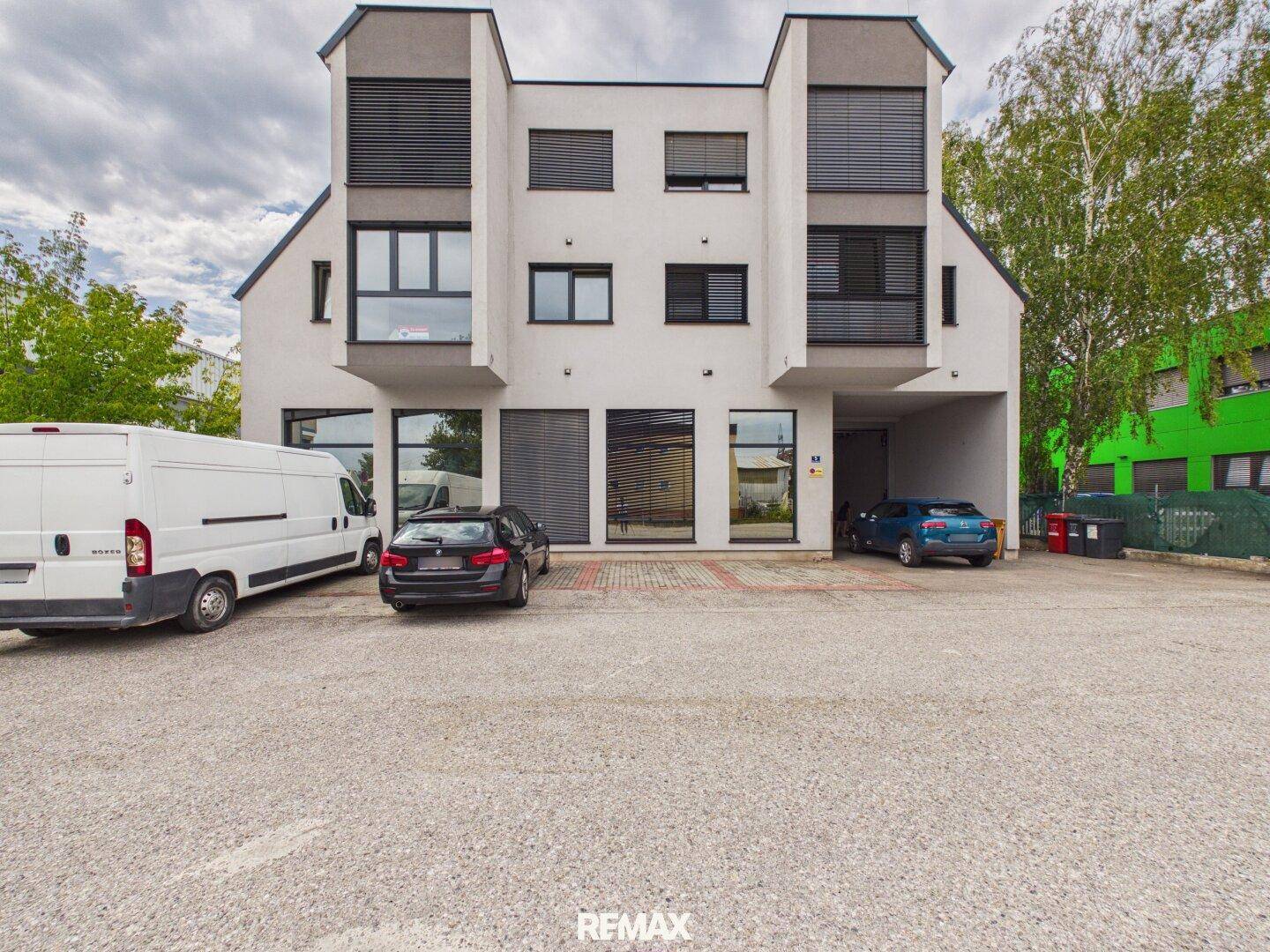 Gesamtansicht der modernen Gewerbeimmobilie mit mehreren Parkplätzen im Vordergrund und einer klaren Architektur.