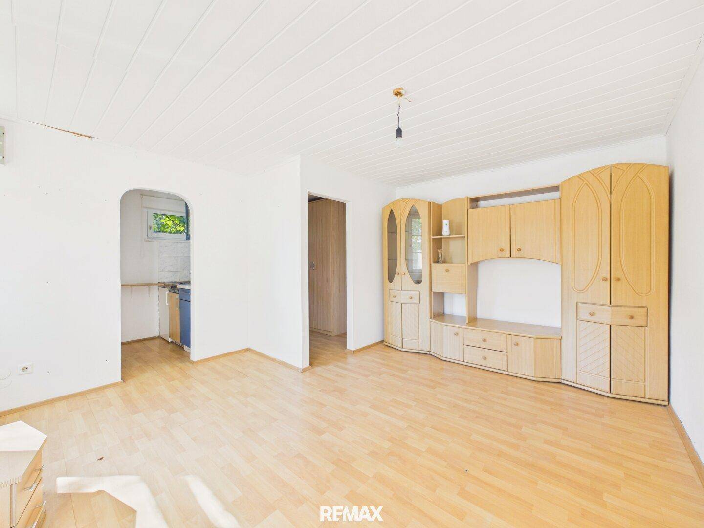 Wohnzimmer mit Laminatboden und einer großen, traditionellen Holzschrankwand.