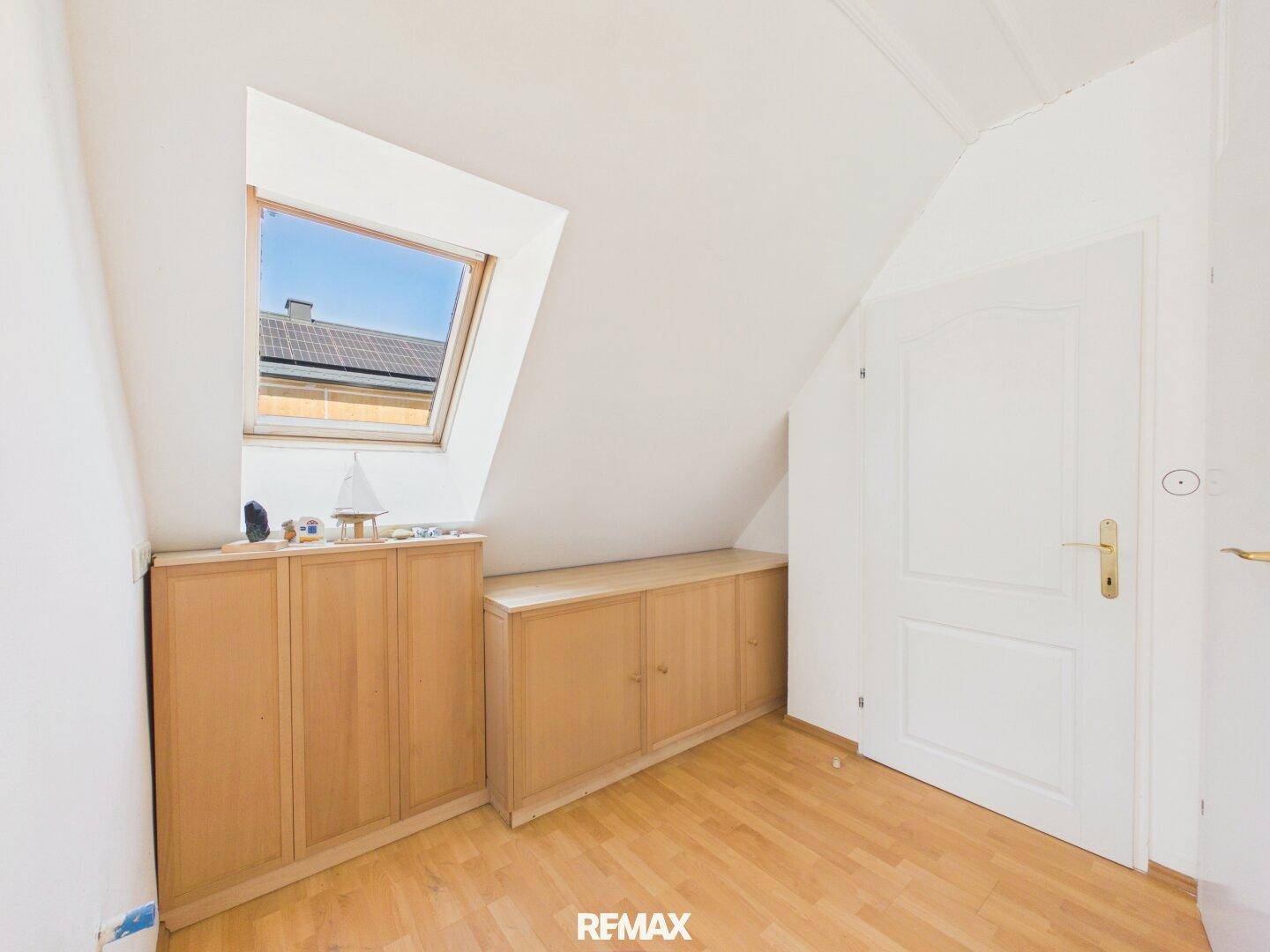 Dachgeschosszimmer mit Einbauschränken, Laminatboden und einem Dachfenster.