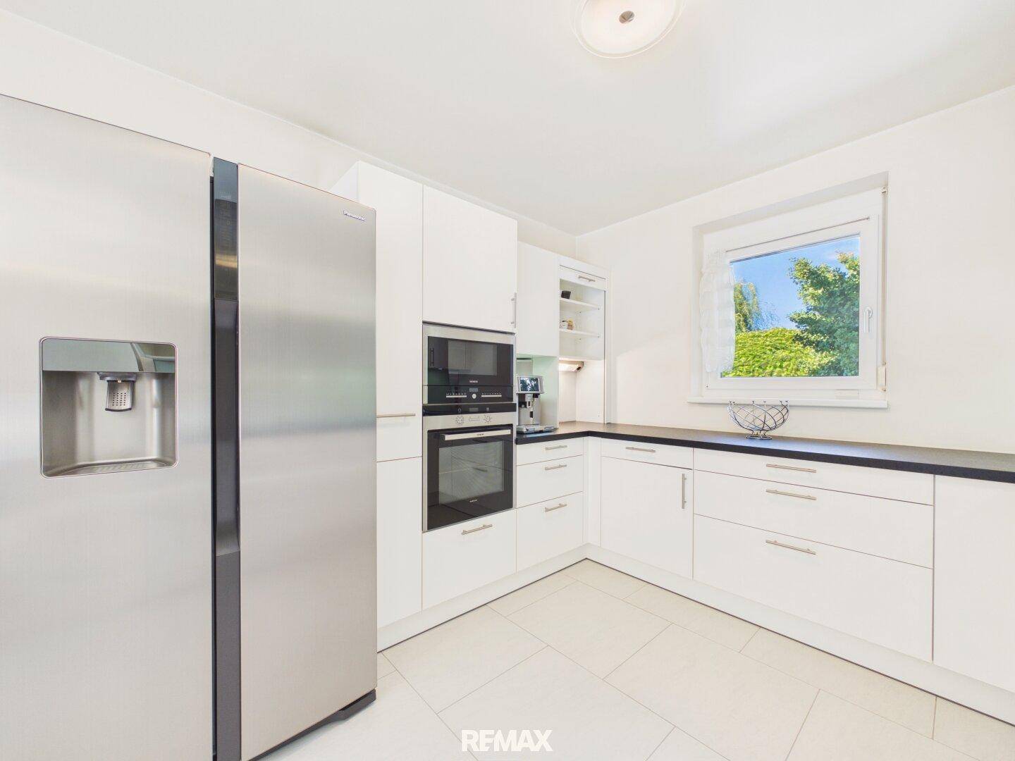 Funktionale Küche mit großem Side-by-Side-Kühlschrank, Backofen und integrierter Kaffeemaschine für Komfort.