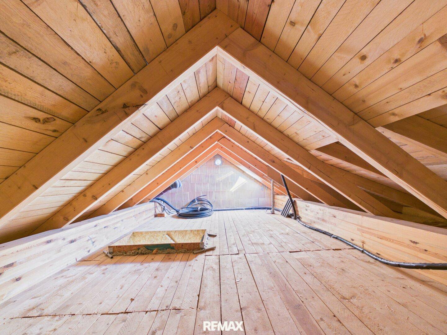 Unausgebauter Dachboden mit sichtbaren Holzbalken und Holzverkleidung, bietet Ausbaupotenzial.