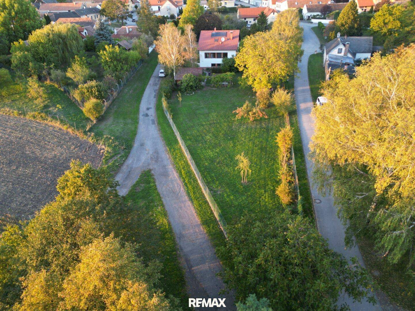 Luftaufnahme eines Einfamilienhauses mit großem Garten und ländlicher Umgebung bei Sonnenuntergang.