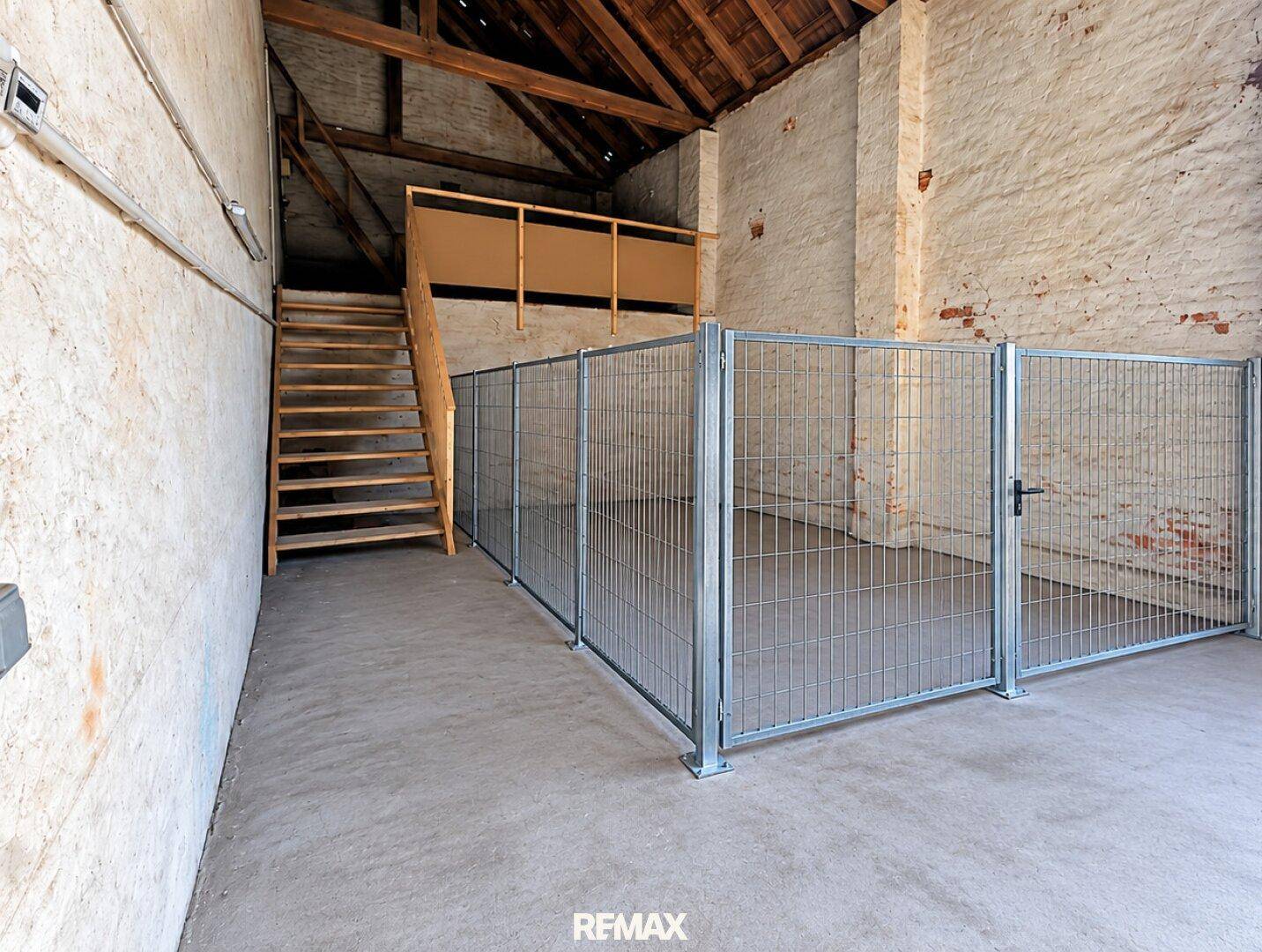 Rustikaler Innenraum mit sichtbaren Holzbalken, einer Holztreppe und einem Betongboden, ideal für Lagerung oder Umbau.
