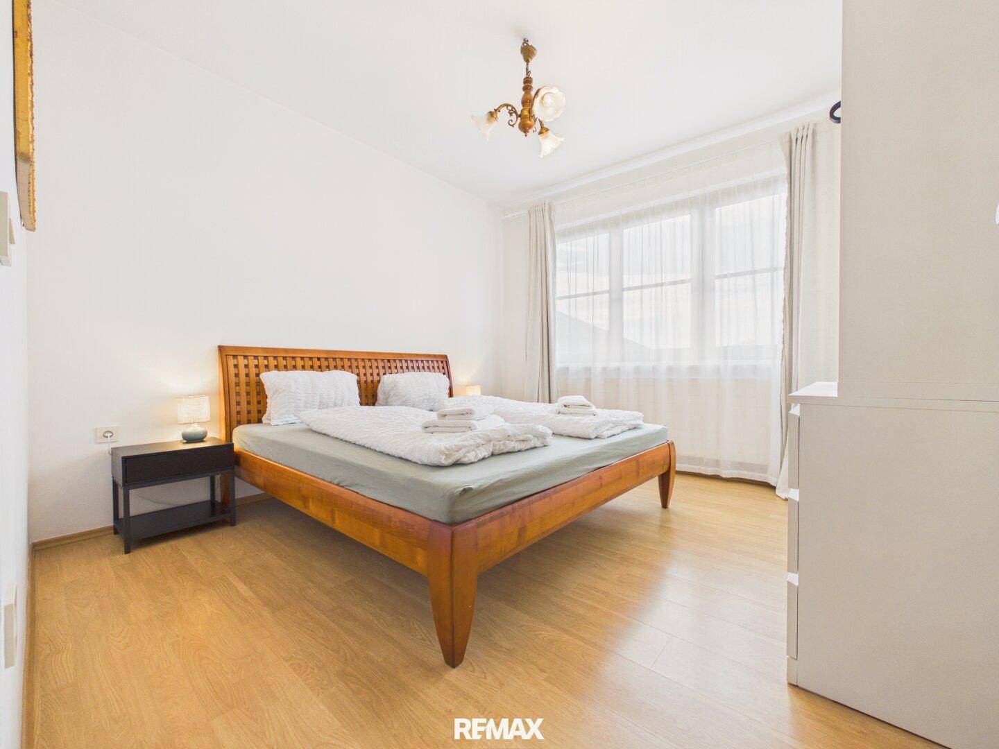 Gemütliches Schlafzimmer mit Holzbett, Nachttischen und großem Fenster für viel Licht.