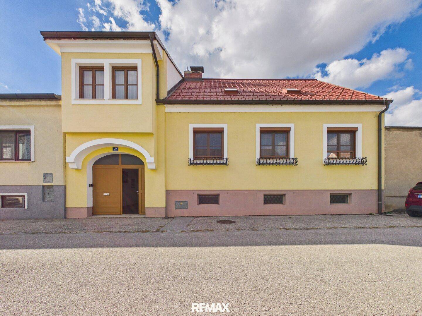 Gelb gestrichenes Haus mit traditioneller Architektur, roten Dachziegeln und Holztüren.