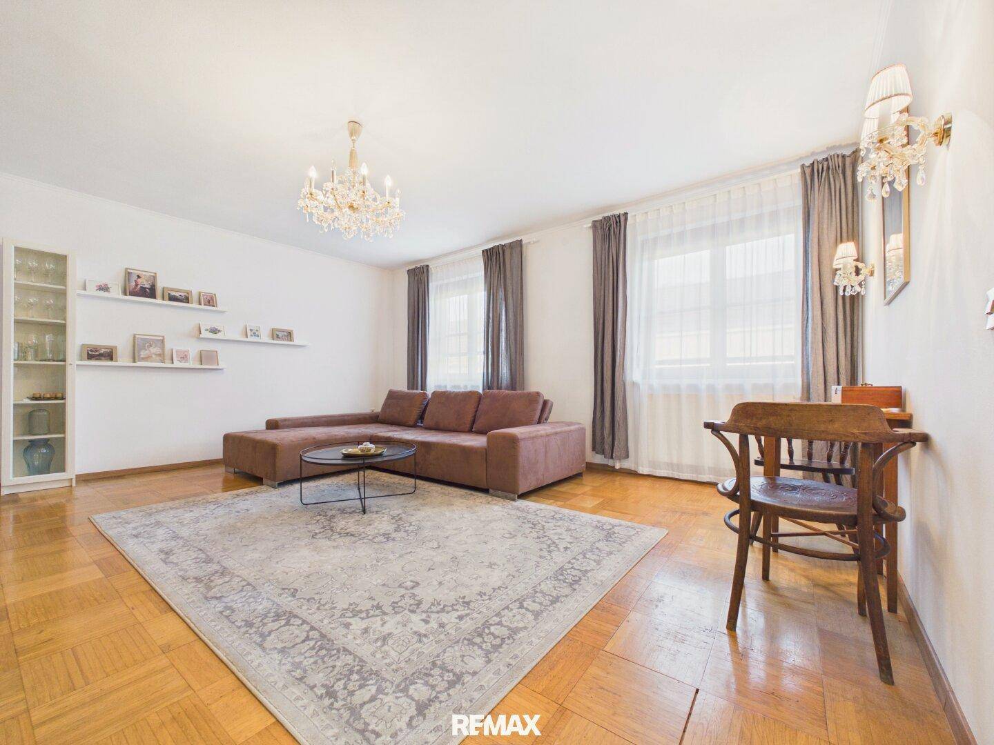 Geräumiges Wohnzimmer mit Parkettboden, bequemer Couch und dekorativen Wandleuchten.