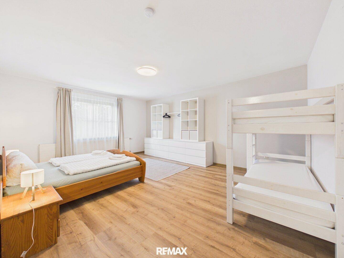 Helles Schlafzimmer mit Doppelbett, Etagenbett und viel Stauraum.