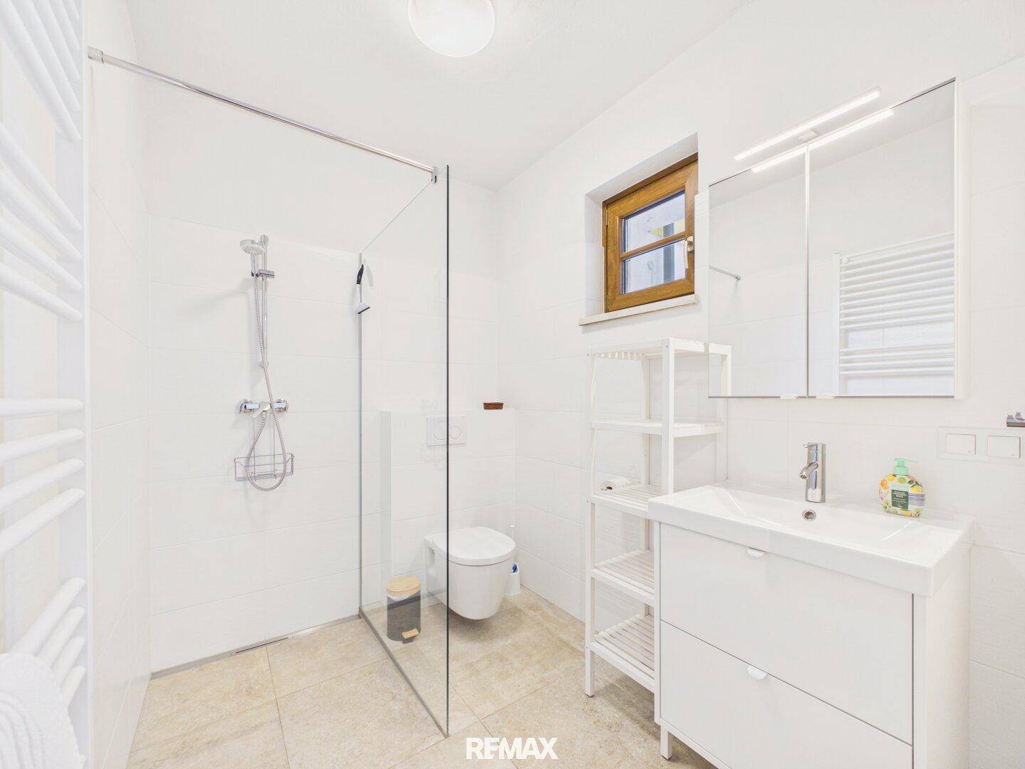Modernes Badezimmer mit ebenerdiger Dusche, Waschbecken und Fenster.