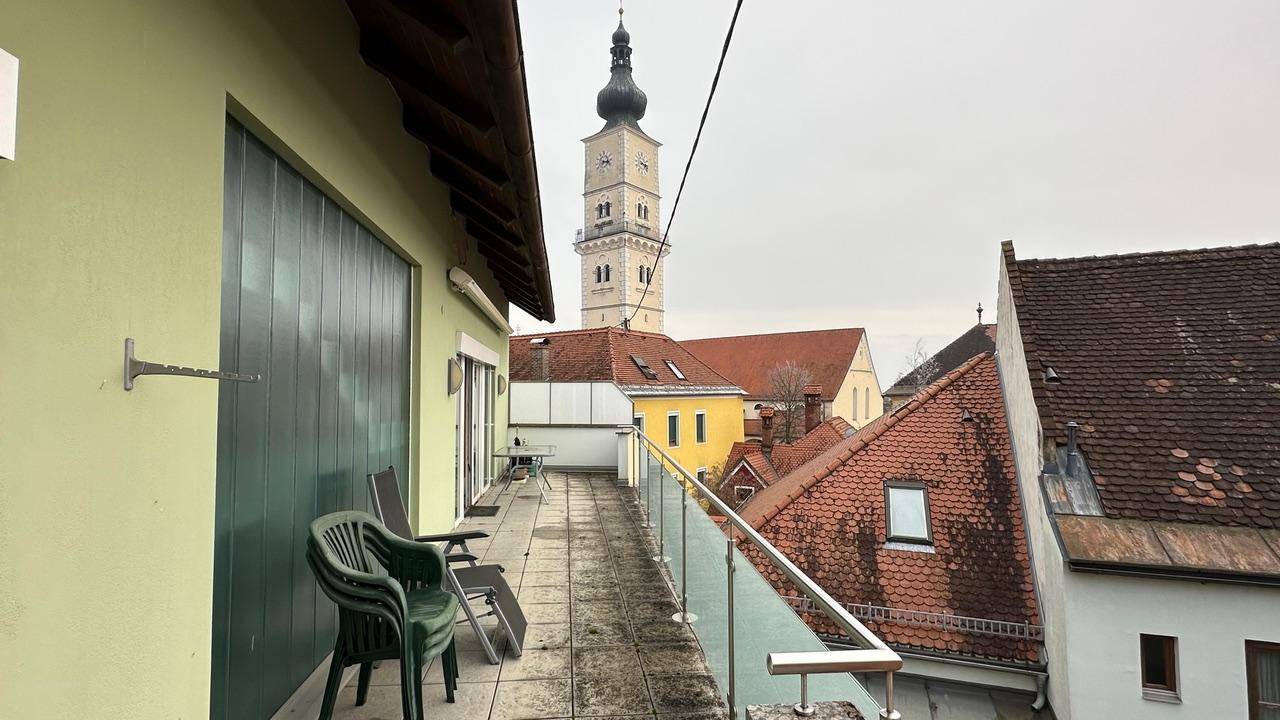 Dachterrasse mit Sitzgelegenheiten und Blick auf die Dächer und den Kirchturm.