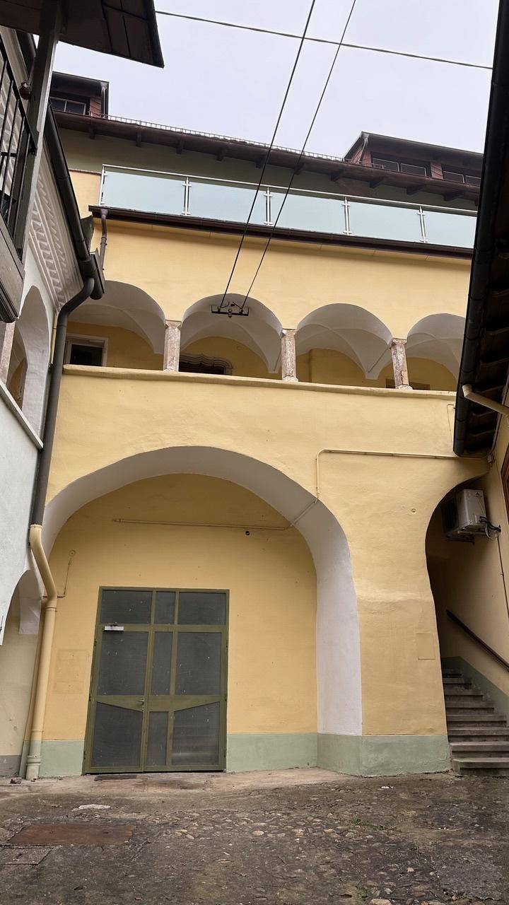 Innenhofansicht eines Gebäudes mit Bögen und einem Balkon im oberen Stockwerk.