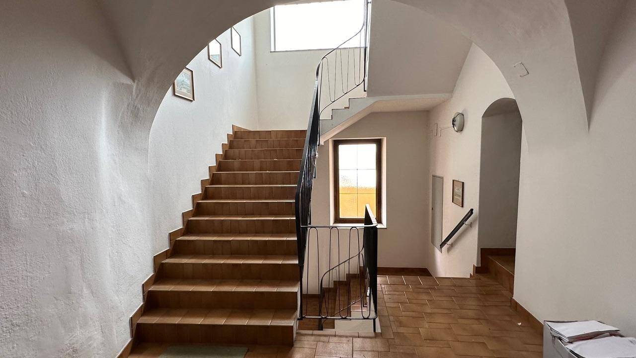 Historisches Treppenhaus mit gefliesten Stufen und gewölbten Durchgängen.
