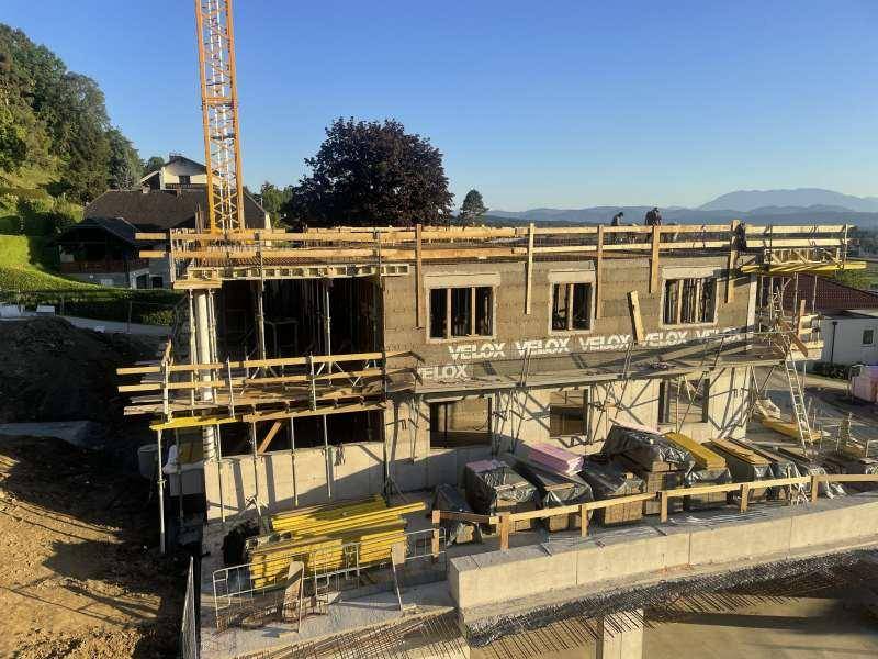Baustelle eines neuen Wohngebäudes mit sichtbaren Konstruktionselementen und Gerüst.