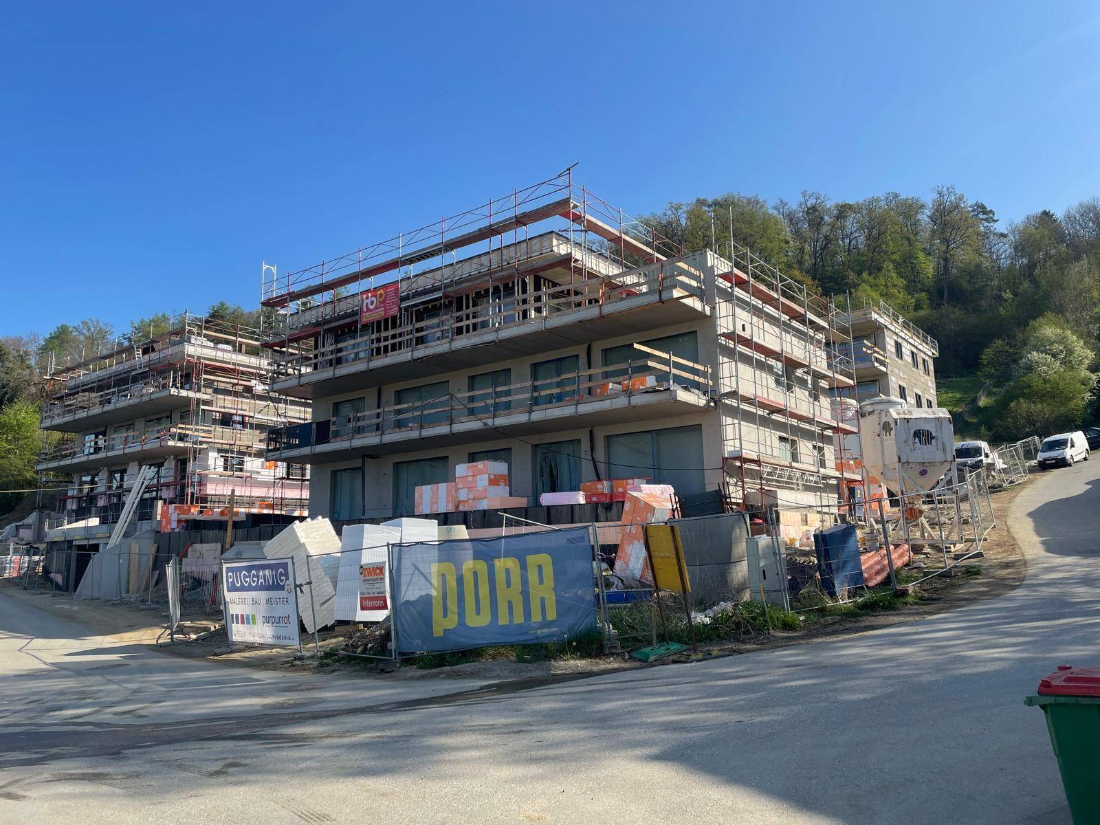 Baustelle mit zwei im Bau befindlichen Gebäuden, Gerüsten und Baumaterialien.