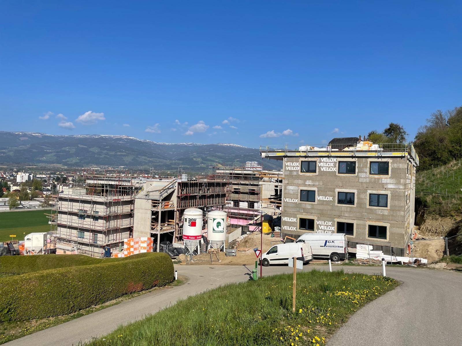 Überblick über die Baustelle mehrerer Gebäude mit Blick auf die umliegende Landschaft und Berge.