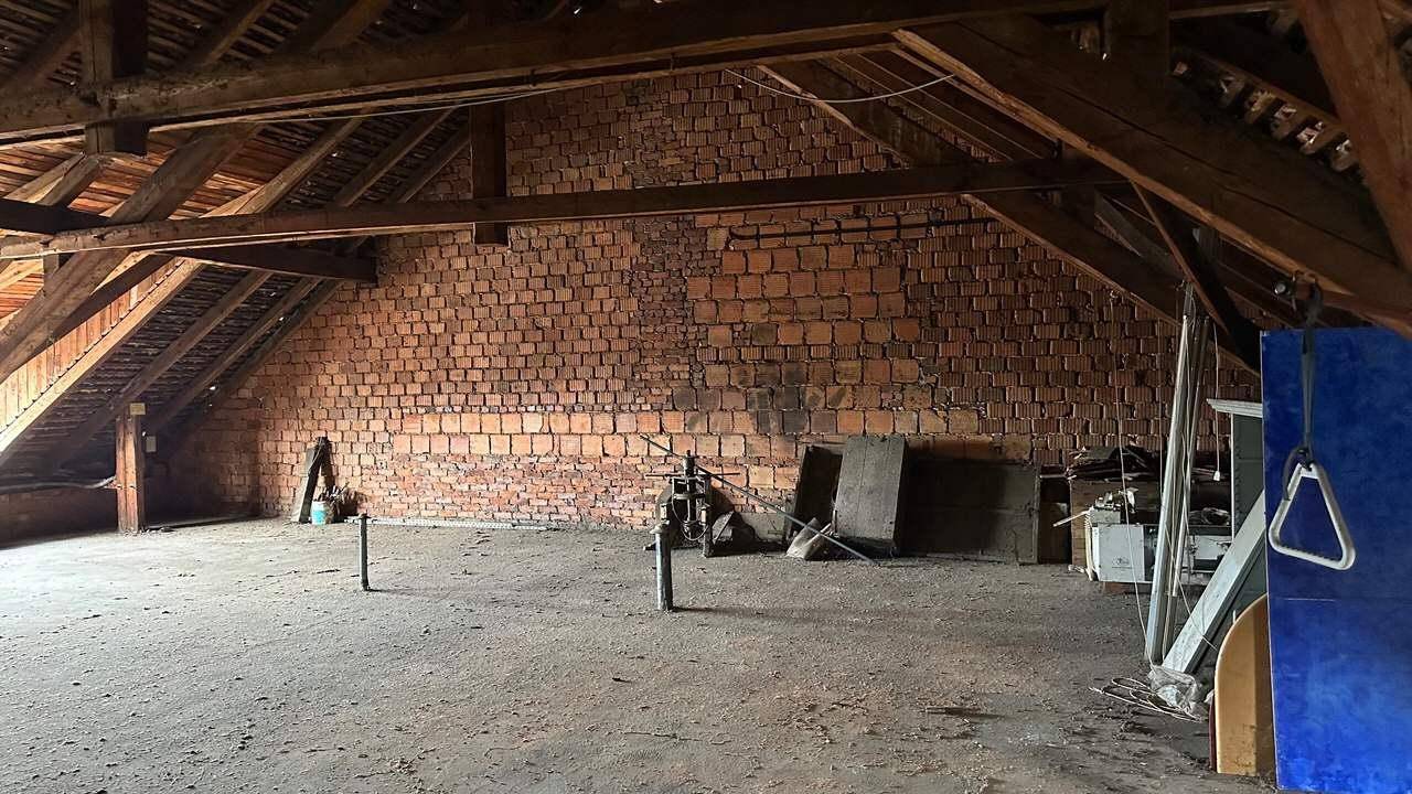 Geräumiger Dachboden mit freiliegenden Ziegelwänden und Holzbalken.