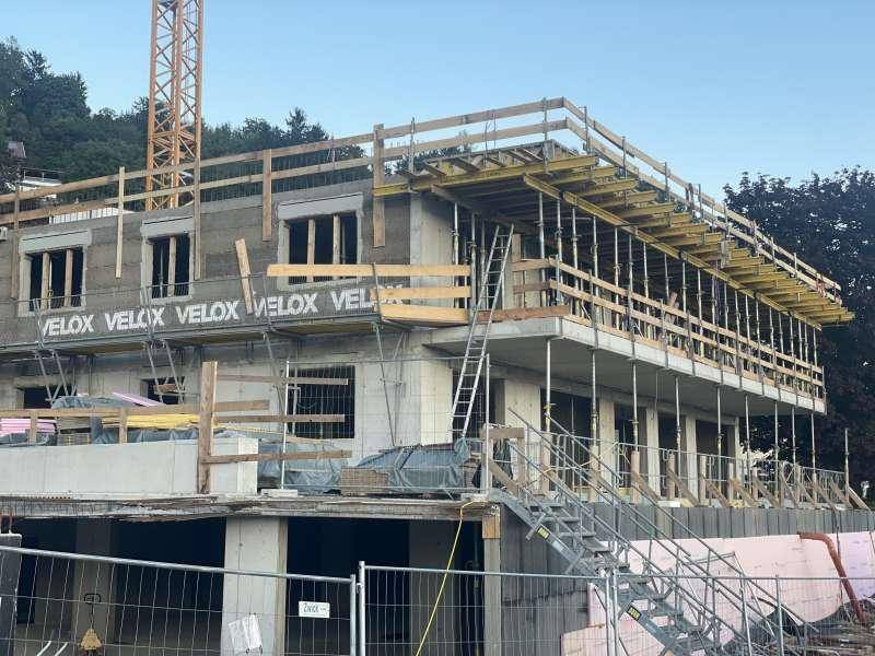 Baustelle eines modernen Gebäudes mit sichtbarer Betonkonstruktion und Gerüst.