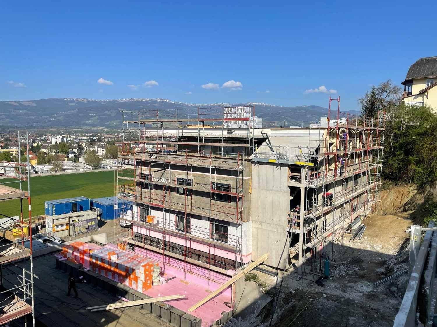 Baustelle mit Blick auf die umliegende Landschaft und die schneebedeckten Berge in der Ferne.