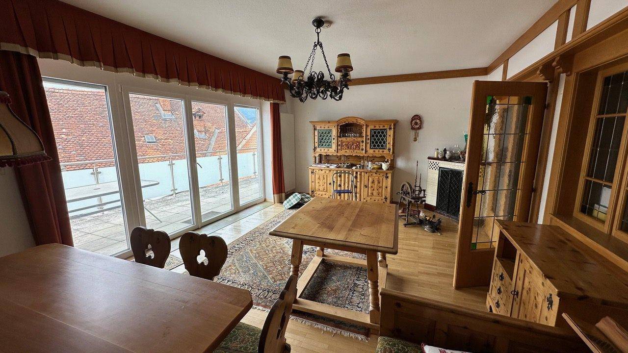 Traditionelles Esszimmer mit Holzmöbeln, Zugang zur Terrasse und Kachelofen.