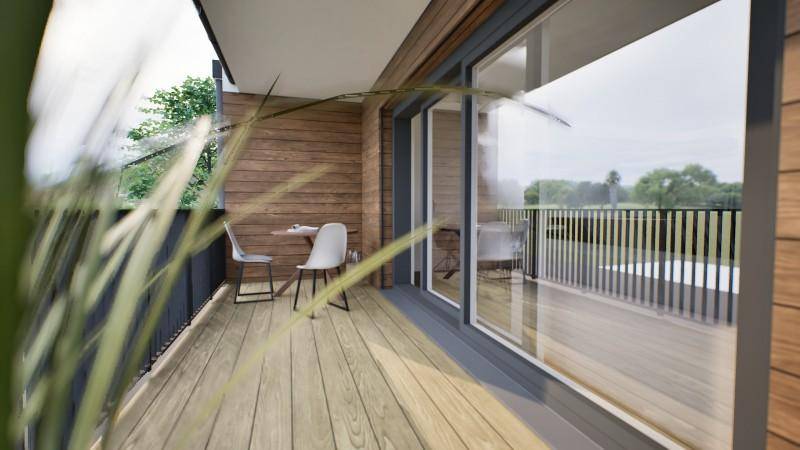 Geräumiger Balkon mit Holzboden, Sitzgelegenheiten und weitem Ausblick ins Grüne.