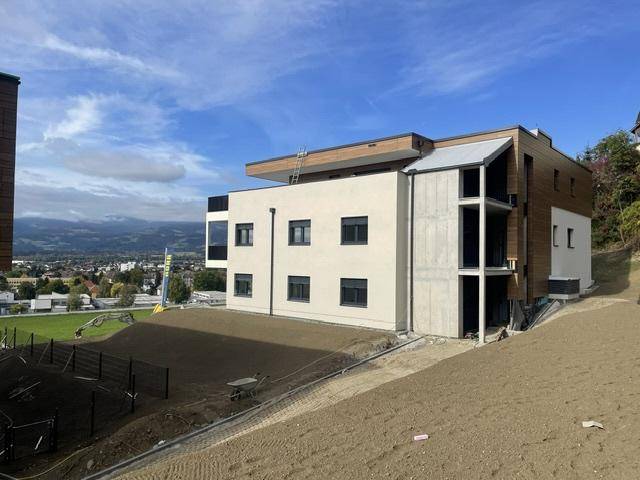Neubauprojekt in Hanglage mit moderner Architektur, Holzfassade und Blick auf die Umgebung.