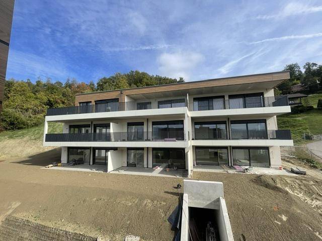 Neubau-Wohngebäude mit moderner Fassade, großzügigen Balkonen und Hanglage im Bau.