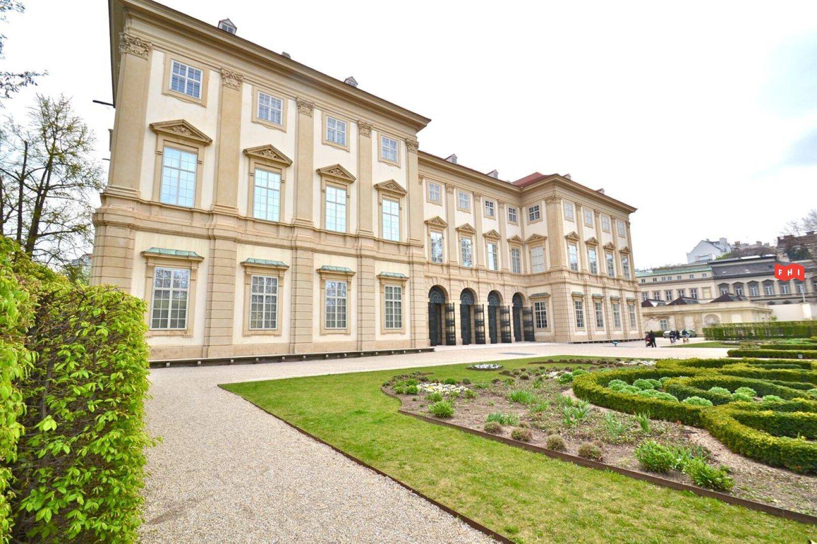 Prächtiger Gartenbereich mit gepflegten Beeten und einem historischen Gebäude im Hintergrund.