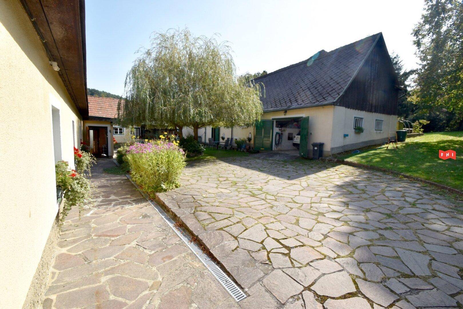 Geräumiger Innenhof mit Natursteinpflaster und Zugang zur Garage des Landhauses.