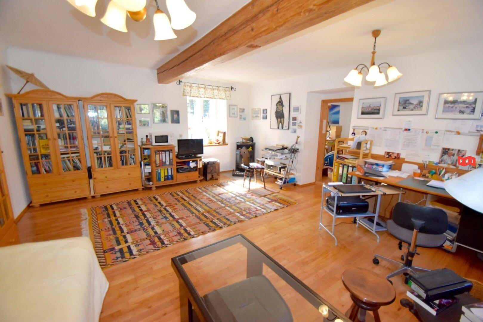 Helles Schlafzimmer mit Holzboden, Bücherregalen und einem Schreibtischbereich.
