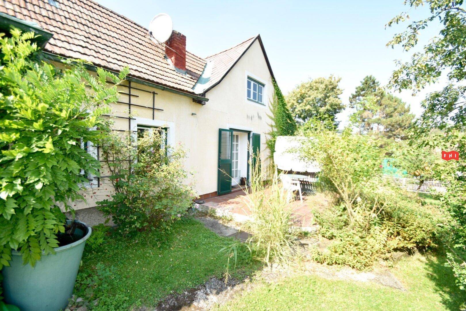 Kleine Terrasse mit Zugang zum Garten, umgeben von grünen Pflanzen.