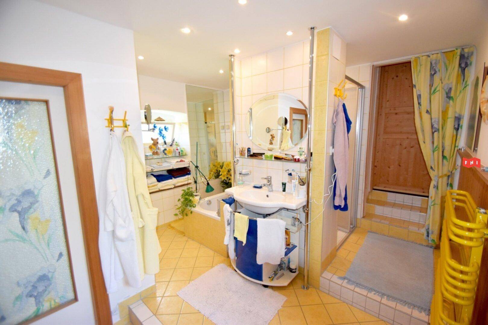 Badezimmer mit gelben Fliesen, Einzelwaschbecken und Badewanne.