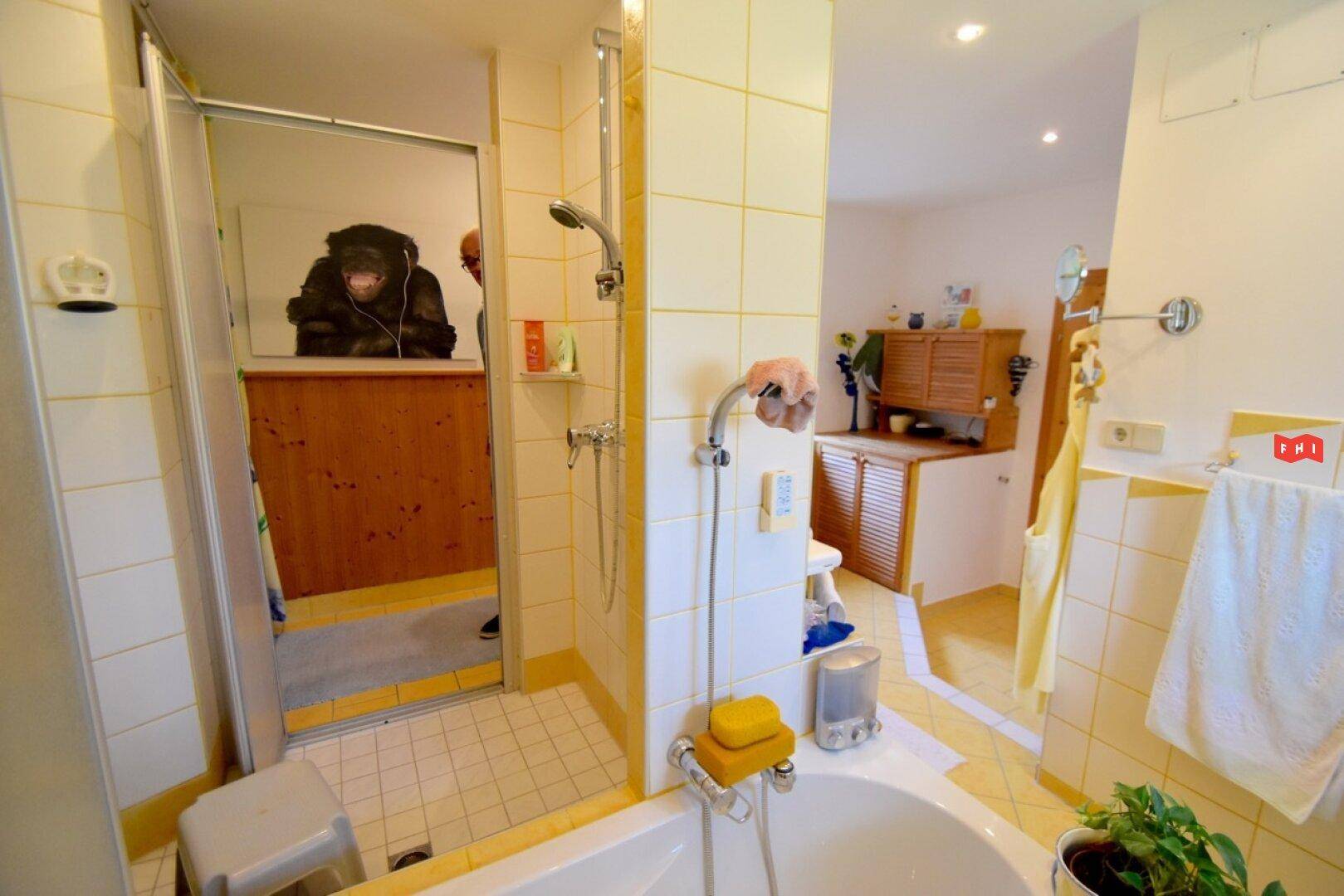 Helles Badezimmer mit Dusche, Badewanne und gelben Fliesen.