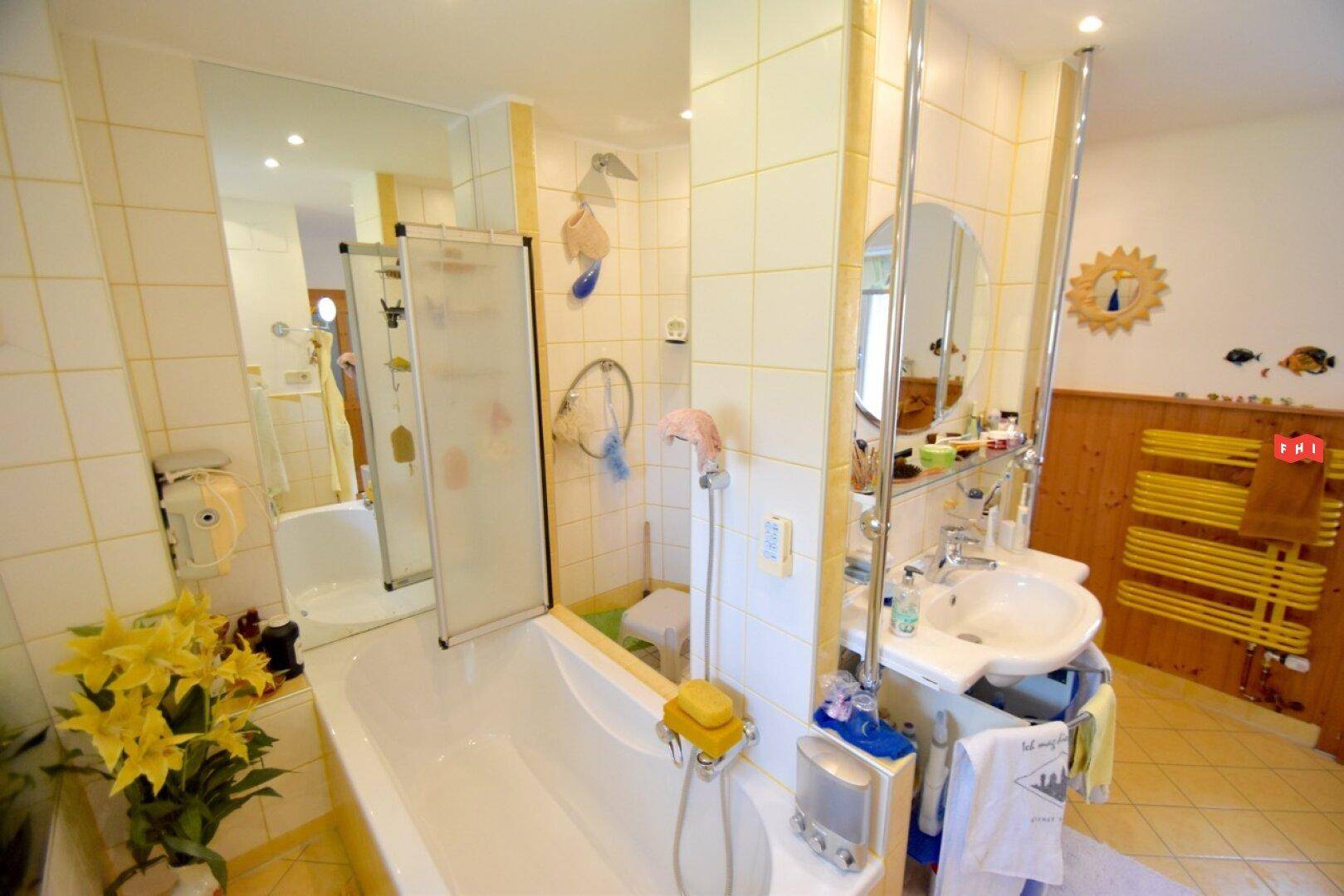 Geräumiges Badezimmer mit Badewanne, Einzelwaschbecken und gelben Fliesen.