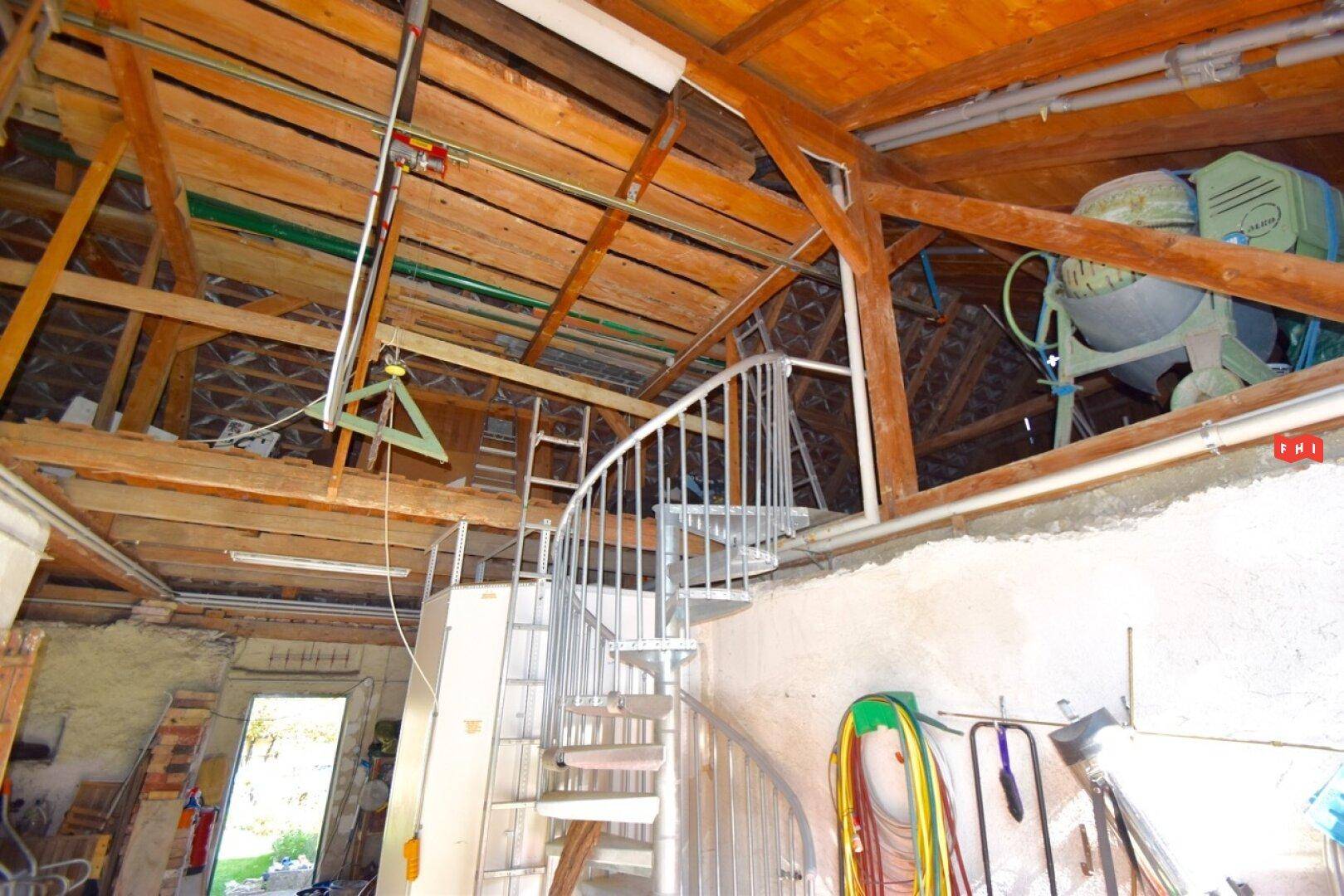 Offener Dachbodenbereich mit Holzkonstruktion und Wendeltreppe.
