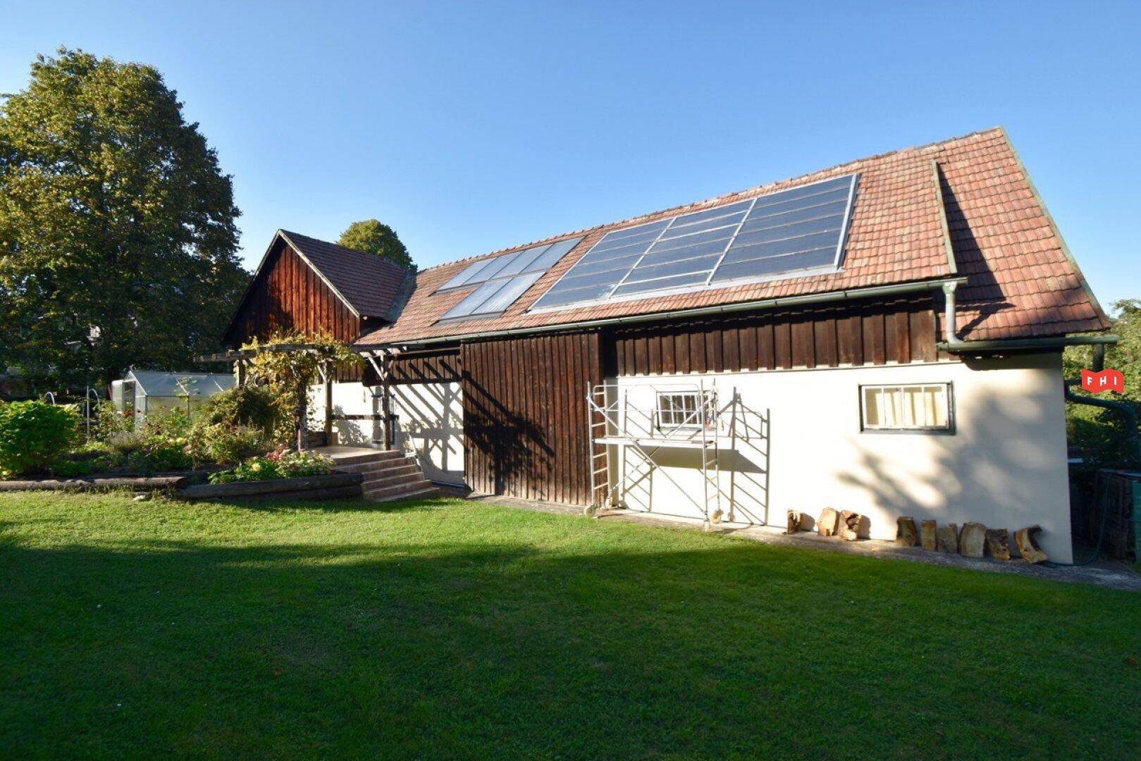Seitenansicht des Gebäudes mit Photovoltaikanlage auf dem Dach und Gerüst an der Fassade.