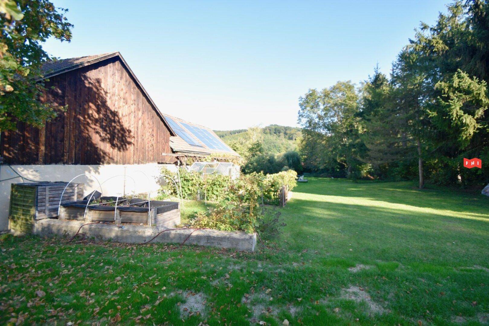 Gartenbereich mit Hochbeeten und Blick auf die umliegende grüne Hügellandschaft.