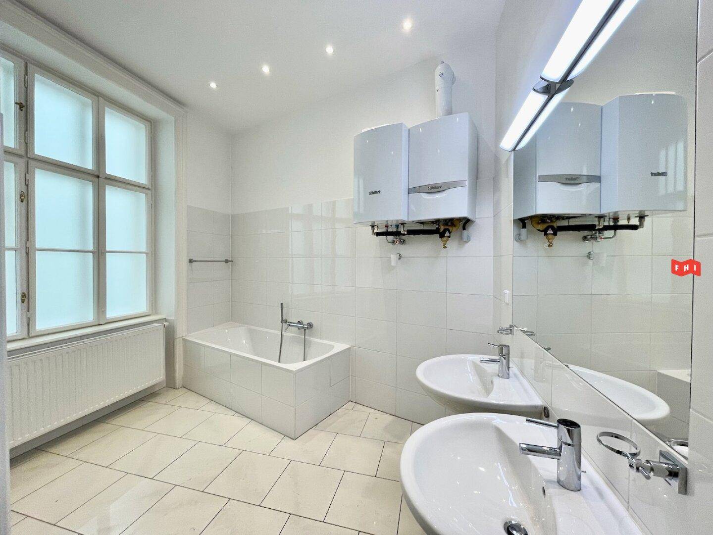 Modernes Badezimmer mit zwei Waschbecken, Badewanne und Wandheizkesseln.