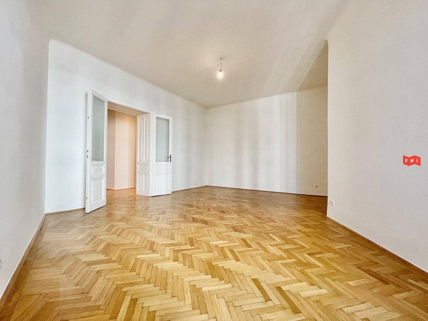 Großzügiges Zimmer mit Fischgrätparkett und Flügeltüren, bereit zur Einrichtung.