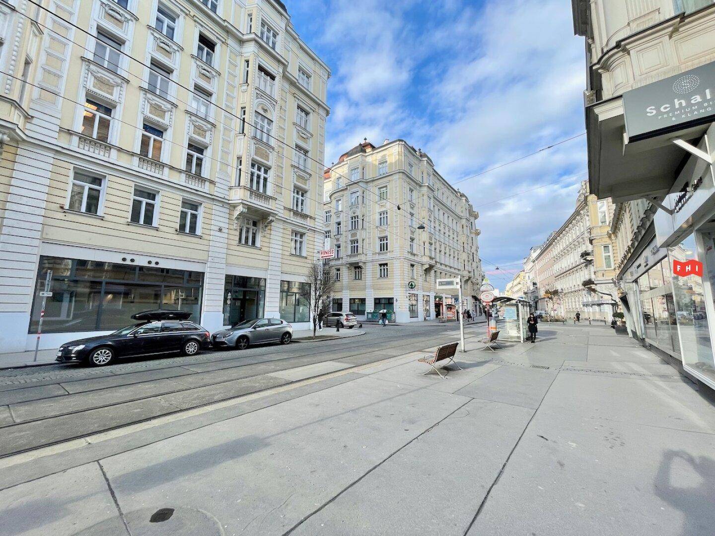Stadtansicht einer belebten Straße mit historischen Gebäuden und Geschäften.