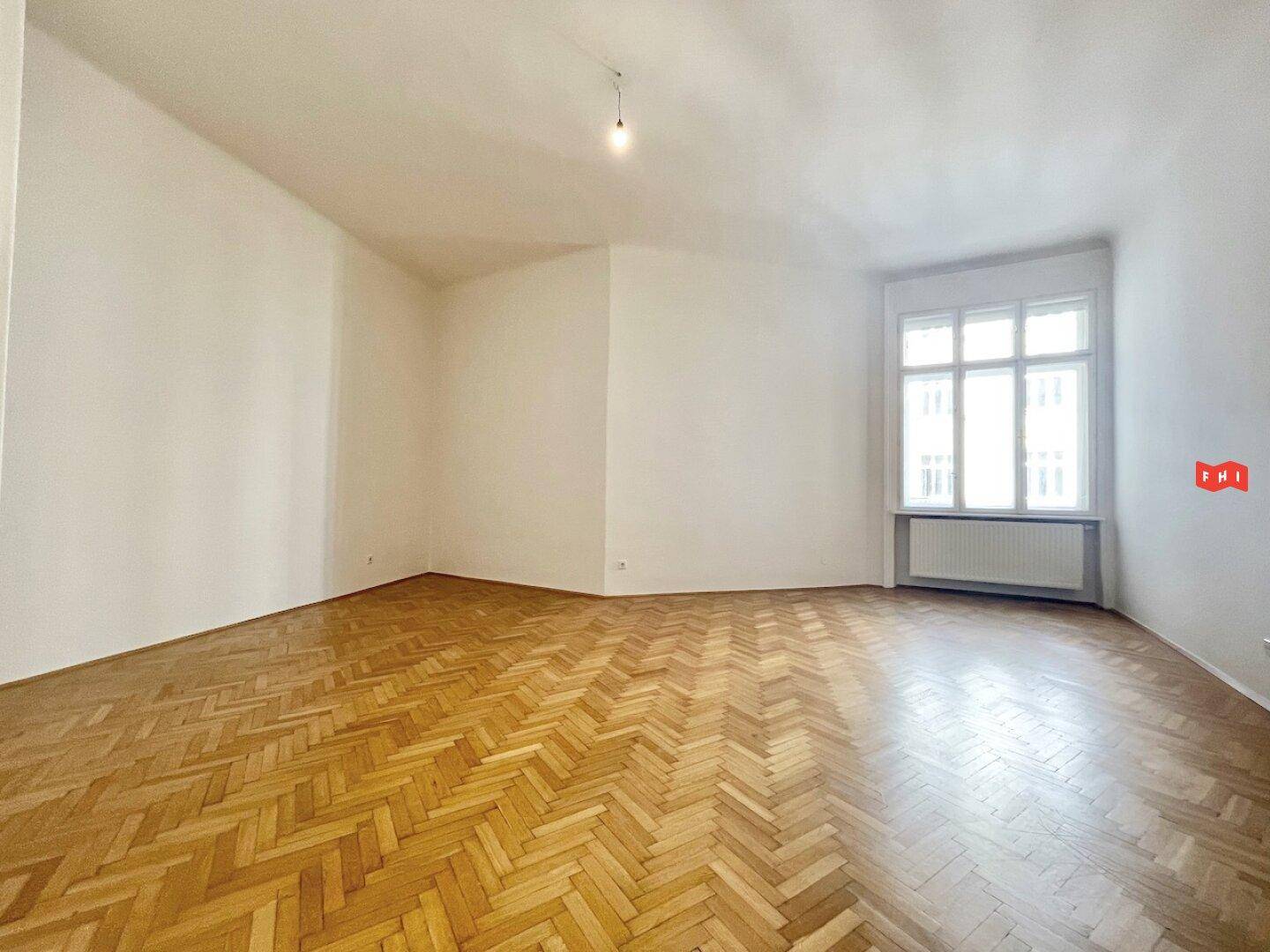 Geräumiger Raum mit Fischgrätparkett und hohen Decken, vielseitig nutzbar.