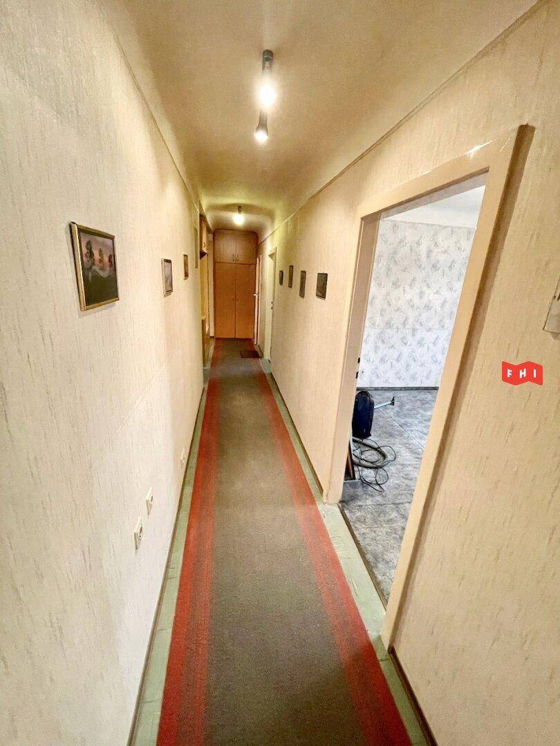 Langer Flur mit Teppichläufer und Einbauschränken am Ende, bietet viel Stauraum.
