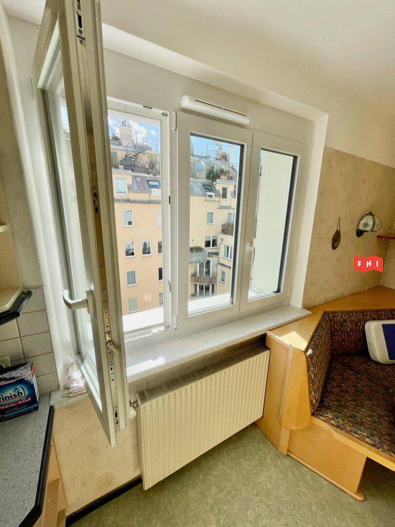 Blick aus dem Fenster der Küche mit Heizkörper und Aussicht auf die umliegenden Dächer.