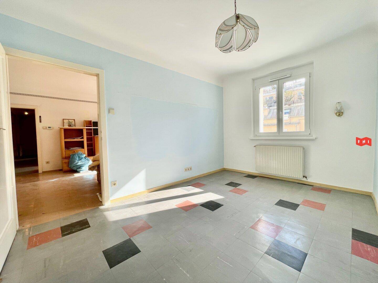 Geräumiges Zimmer mit blauen Wänden und einem markanten Fliesenmuster, hell und einladend.