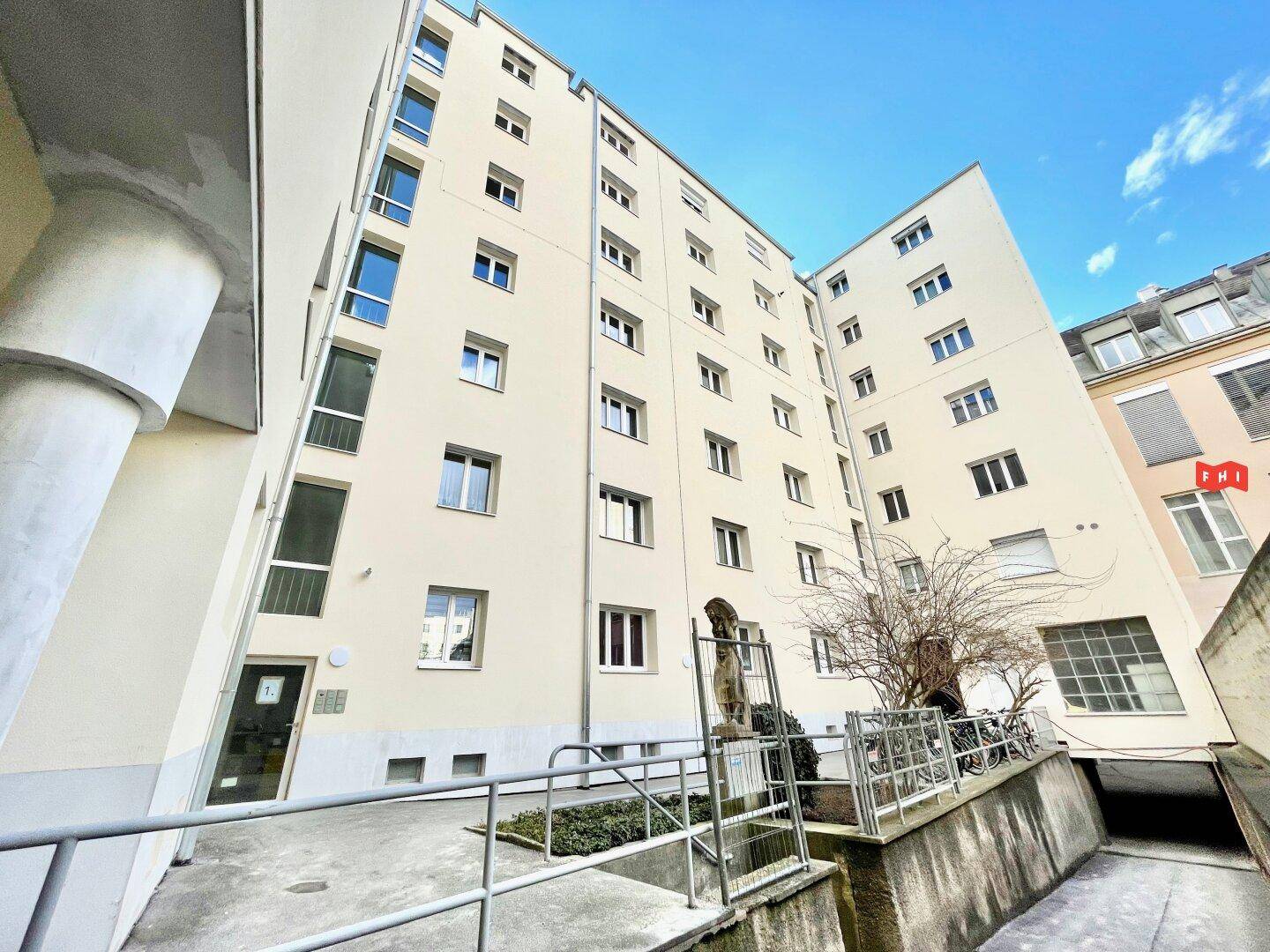 Fassade des Gebäudes vom Erdgeschoss aus mit Eingangsbereich und einer Rollstuhlrampe.