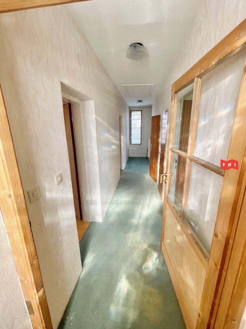 Heller Flur mit Teppichboden und Holztüren, der zu weiteren Räumen führt.