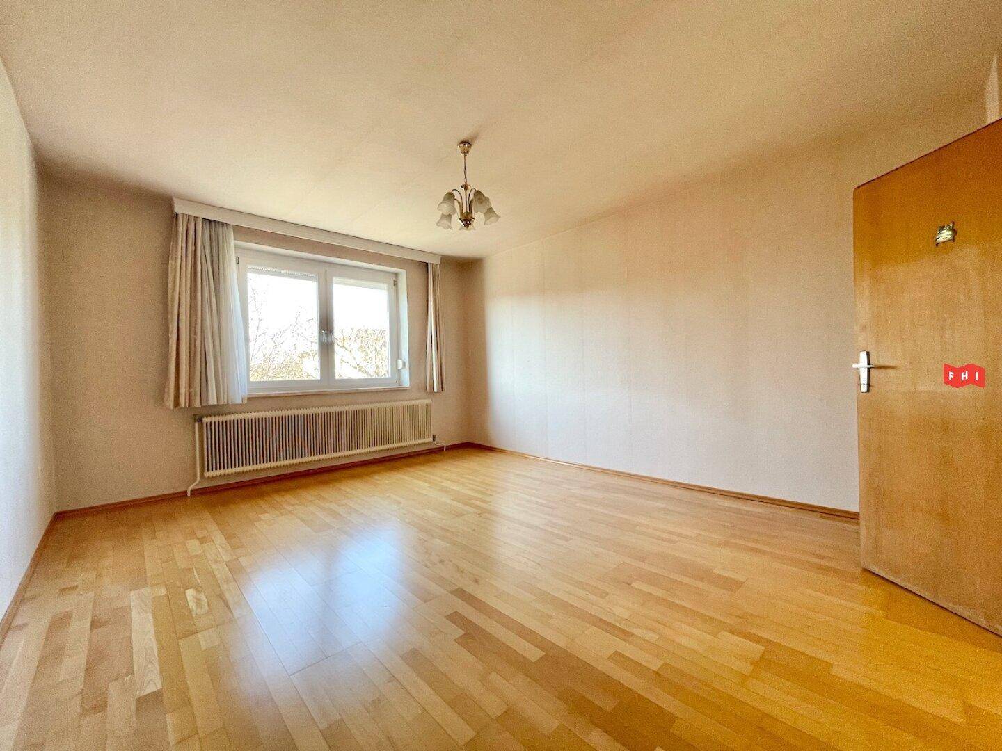 Geräumiges Schlafzimmer mit Parkettboden, großem Fenster und viel natürlichem Licht.