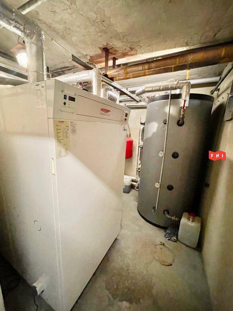 Heizungsraum im Keller mit großem Heizkessel und Warmwasserspeicher.